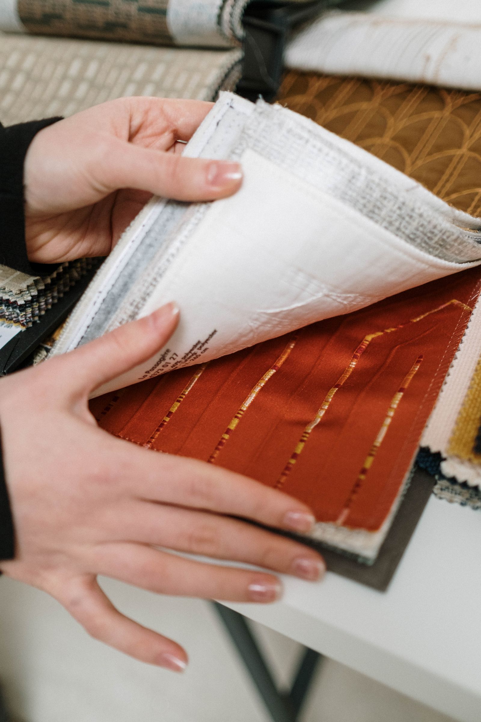 Hands turning labelled fabric swatches during material review