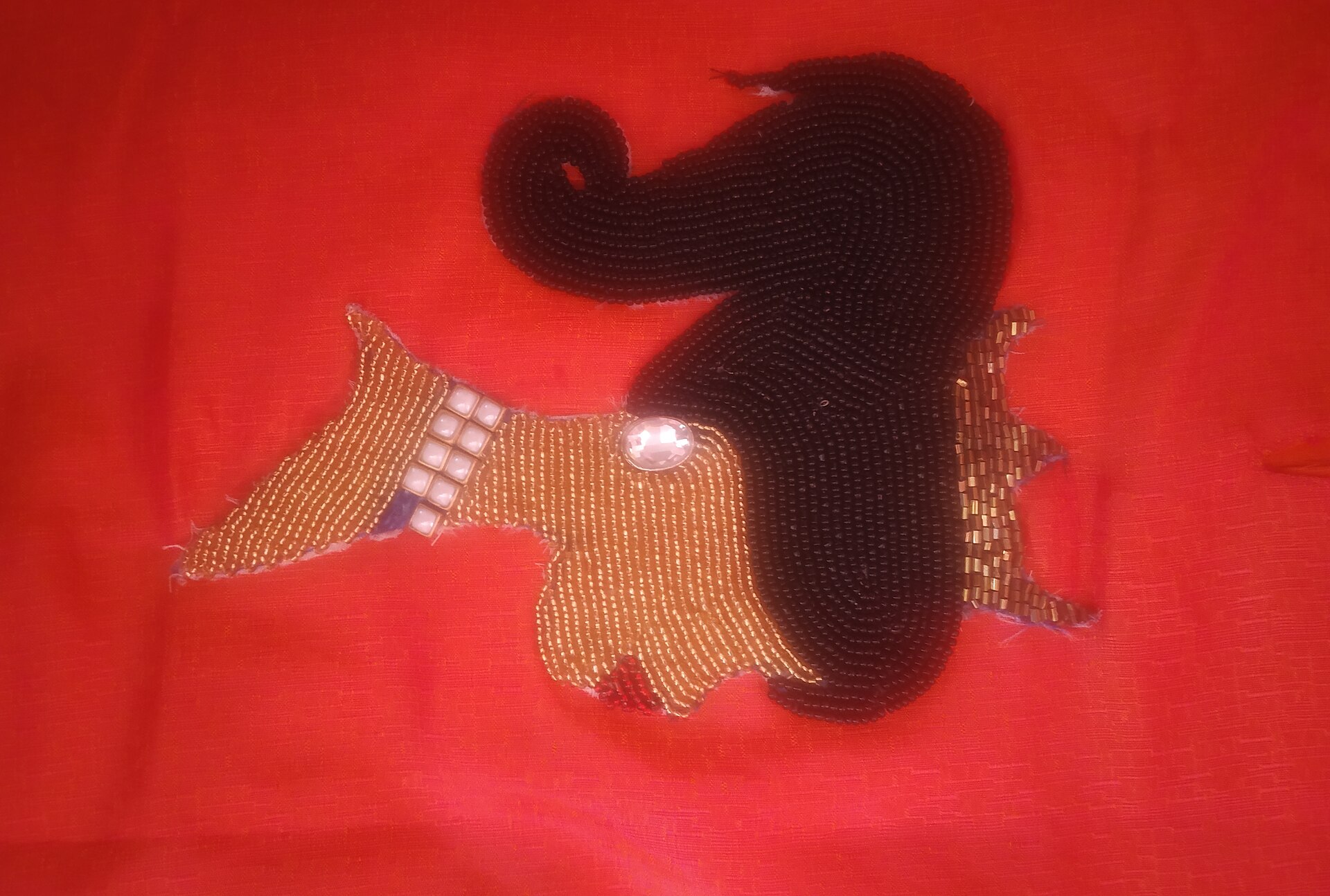 Close view of bead rows and embroidered edges on red fabric