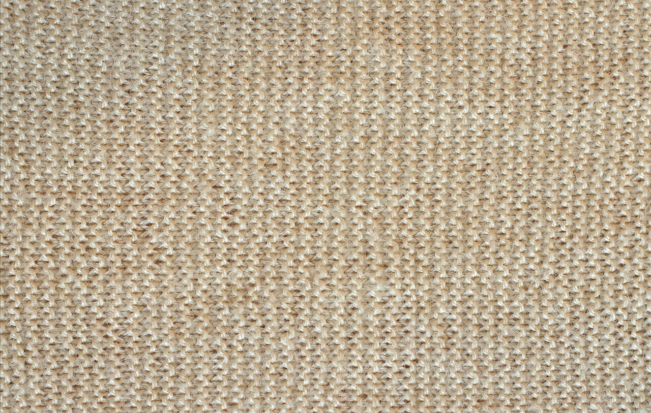 Close view of beige wool fabric showing the woven yarn structure