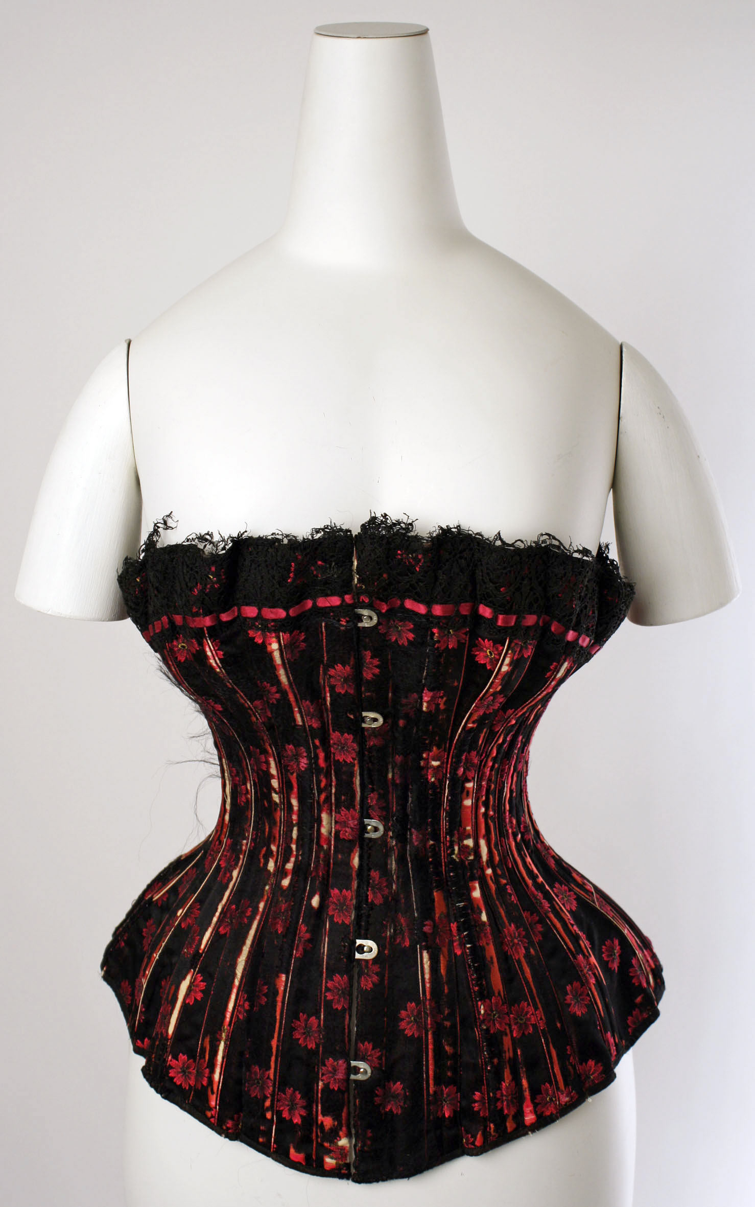 Historical black and red corset showing shaped panels, vertical stays and a front closure