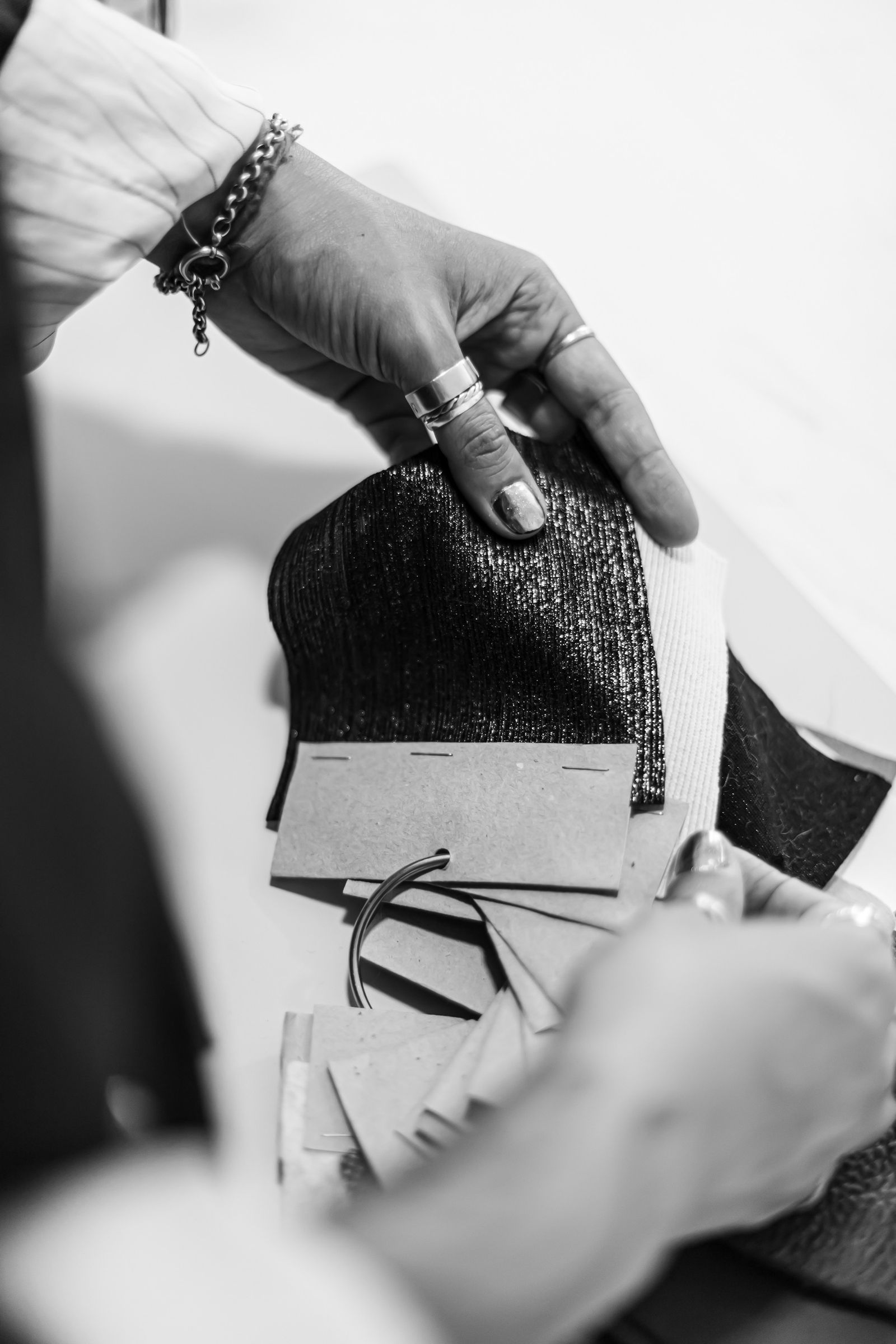 Hands reviewing labelled fabric swatches in a sampler