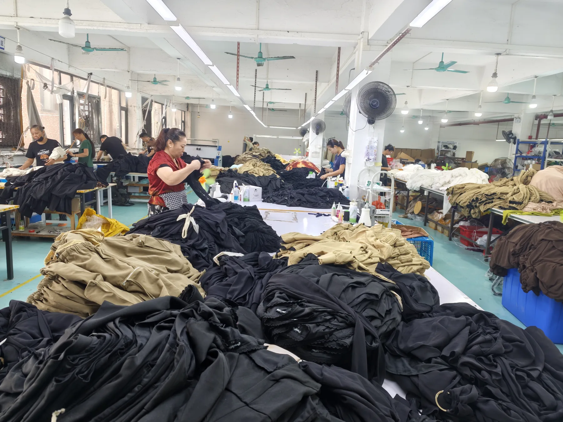 Wide view of garment finishing and batch handling tables in the PIPK factory